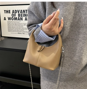 Detailed shot of a khaki hobo handbag with white stitching and stylish chain strap