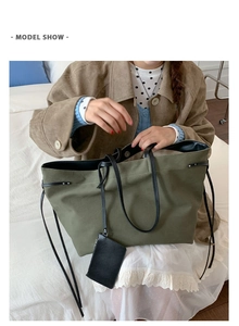 Model wearing a large army green tote bag with drawstring details and a small pouch