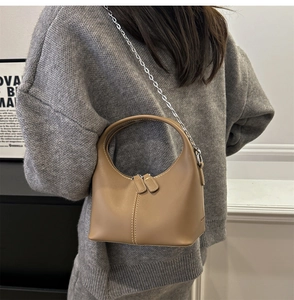 Detailed close-up of a crescent-shaped leather crossbody bag with silver chain straps