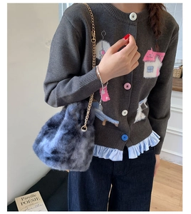 Detail view of a gray marble faux fur bucket bag with a golden metal chain strap