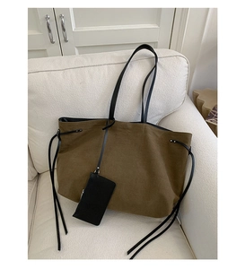 Detail of olive suede tote bag with black leather straps and matching small pouch