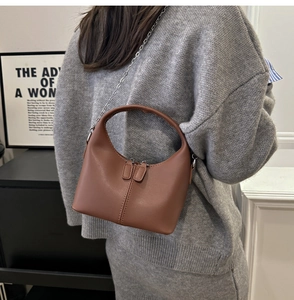 Detail of brown leather hobo bag with dual metal zippers and elegant chain strap