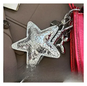Detail of silver star charm with crackle texture on a metallic red crossbody bag