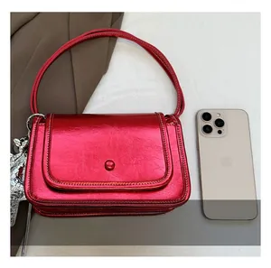 Mini metallic red crossbody bag with silver hardware compared to smartphone for size scale