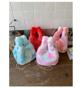 Detail of plush faux fur handbags with gold chains in blue, red, and pink tie-dye patterns