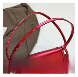 Detail of metallic red handbag handle featuring white contrast stitching and shiny finish