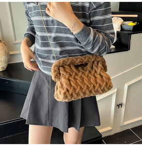 Détail de la texture tricotée épaisse et de la chaîne dorée du sac tissé marron