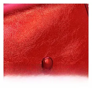 Macro shot of metallic red litchi texture leather and meticulous stitching on crossbody bag