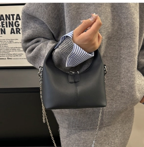 Detail of minimalist black chain bag featuring matte leather and silver zippers