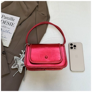 Detail of metallic red crossbody bag with star pendant on fashion magazine layout