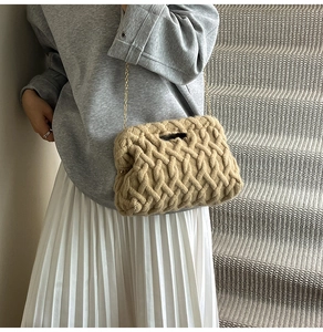 Détail d'un sac en grosse maille kaki avec chaîne dorée sur un sweat-shirt gris