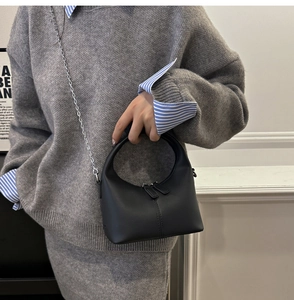 Detail of black leather half-moon bag with silver chain strap and matte finish
