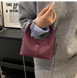 Detail view of burgundy crescent handbag with matte leather finish and silver chain strap