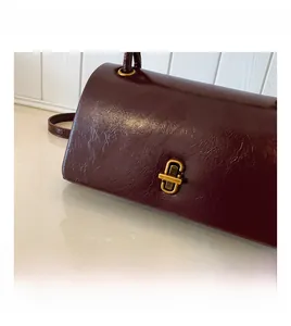 Detailed close-up of golden metal rotating lock on premium burgundy leather handbag