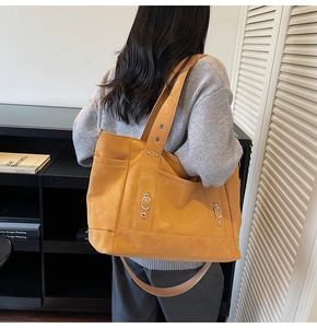 Détail du sac cabas jaune avec anneaux en métal argenté et rivets sur les poches de côté