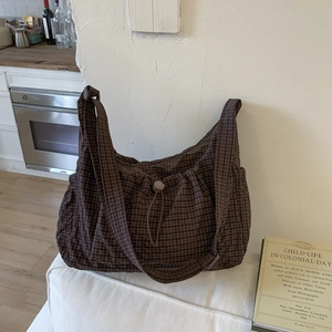 Sac bandoulière en toile à carreaux marron avec cordon de serrage et style minimaliste