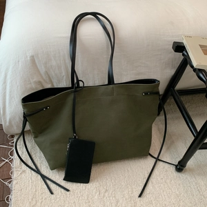Olive green canvas tote bag with black leather handles and matching small pouch