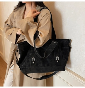 Détail d'un grand sac cabas noir mat avec boucles argentées et texture élégante