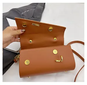 Detail of premium golden magnetic buckles and PU leather finish on a brown crossbody bag