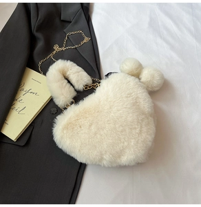 Detail der cremeweißen Plüschtasche in Herzform mit Goldkette und weichen Bommeln