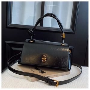 Detail of black glossy faux leather bag with vintage gold twist lock on prop book
