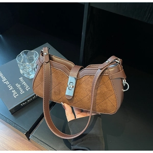 Detail of dark brown patchwork baguette bag with suede texture and silver twist lock