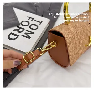 Detail of adjustable brown leather shoulder strap with gold metal buckle on woven bag