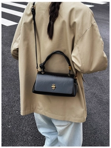 Detail view of the black leather shoulder bag with gold twist lock and knotted handle