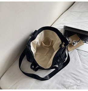 Détail du sac cabas en toile noire avec doublure en tissu beige et poche intérieure zippée