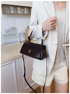 Close-up of black oil wax leather handbag with gold vintage twist lock and knotted handle