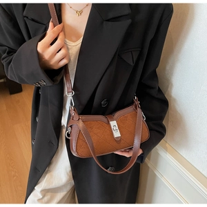Detail of retro brown suede bag with diamond stitching and metal buckle closure