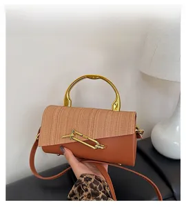 Detail view of contrast color box bag with gold metal handle and woven leather texture