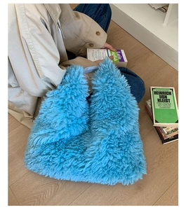 Detail einer himmelblauen Plüschtasche mit weichem Webpelz auf einem Holzfußboden