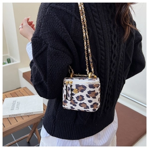 Détail du sac boîte léopard avec boucle fleur dorée et bandoulière sur pull noir