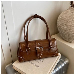 Detail of brown glossy pleated shoulder bag with silver studs on a suitcase