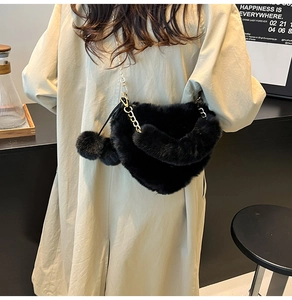 Detail der schwarzen Herz-Plüschtasche mit Goldkette und Bommelanhängern am Model