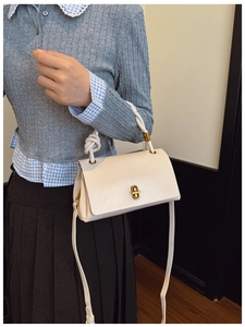 Detail of cream shoulder bag with golden twist lock and unique knotted handle decoration