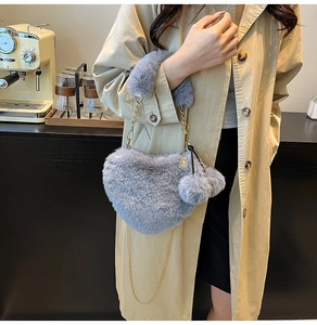 Nahaufnahme der herzförmigen grauen Kunstfell-Handtasche mit goldener Kette und Bommel
