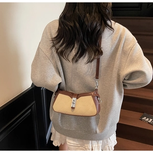 Detail of contrast stitch baguette bag with silver twist lock and quilted texture