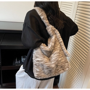 Model wearing large grey striped faux fur tote bag showing crossbody style and texture