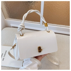 Detail of white PU shoulder bag featuring a unique rope knot handle and gold turn-lock closure