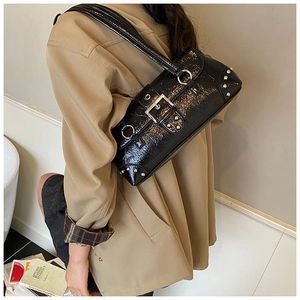 Detail of black glossy crossbody bag with silver buckle and metal rivet accents