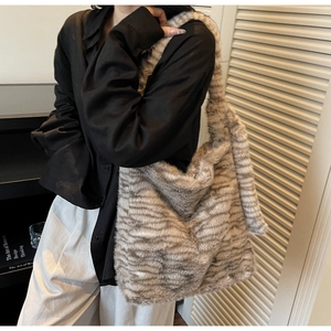 On-shoulder view of large faux fur tote bag with striped pattern for autumn winter