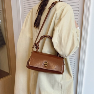 Detail of vintage brown leather bag with golden twist lock on beige autumn coat