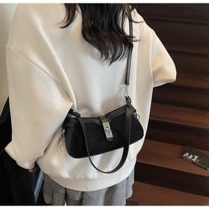 Detailed view of black quilted crossbody bag featuring silver metal buckle and slim strap