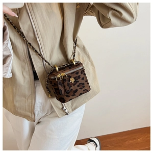 Détail du mini sac boîte imprimé léopard avec breloque fleur dorée et bandoulière