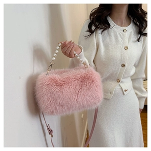 Detail of pink faux fur handbag with elegant white pearl handle and metal strap hooks