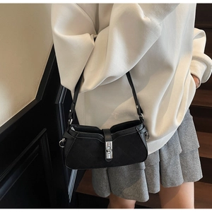 Close-up of black quilted baguette bag with silver metallic twist lock closure