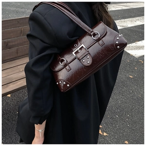Close-up of vintage dark brown cracked leather shoulder bag with silver buckle and rivets