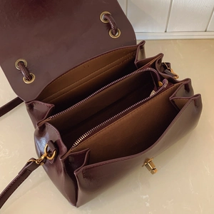 Interior detail of burgundy leather bag showing three compartments and gold-tone hardware